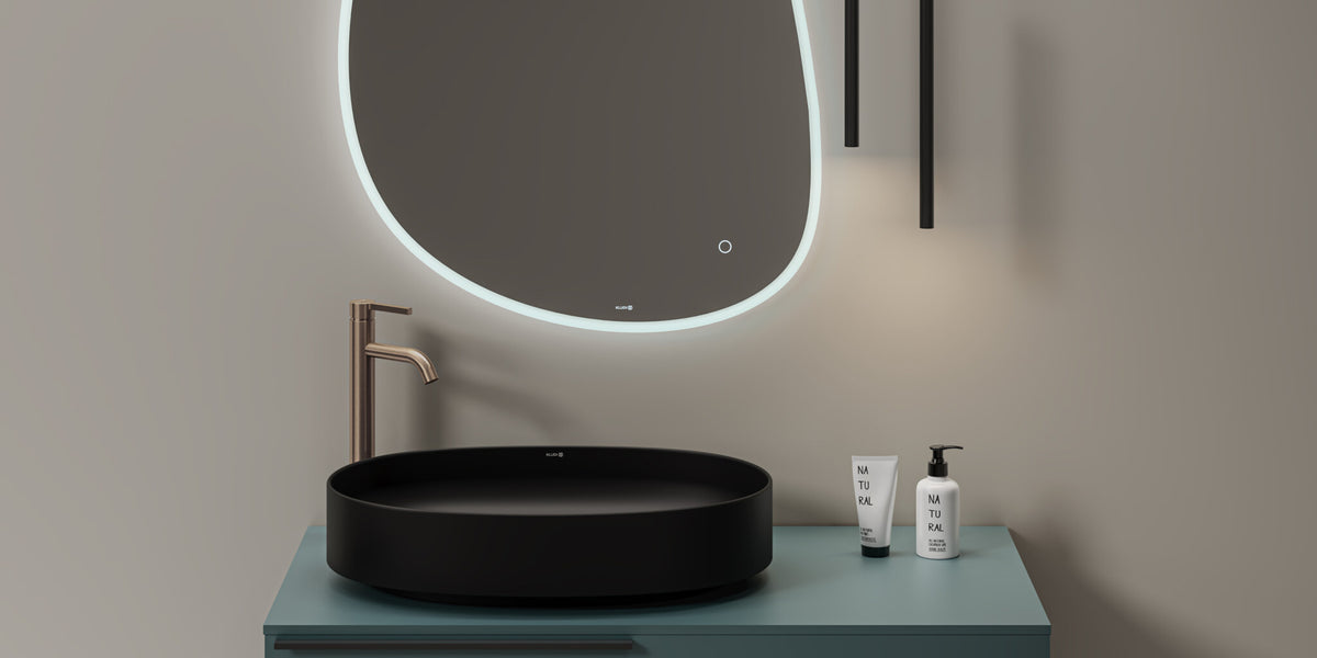 Tall deck-mounted basin mixer on a black bowl basin under a backlit mirror
