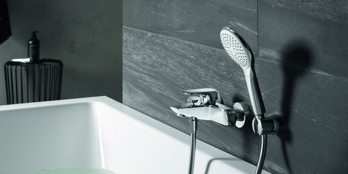 Bath mixer with a hand shower on a slate wall above a white bath