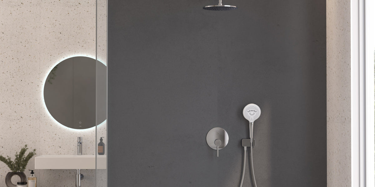 Shower place with a hand shower on a grey wall beside a lit round mirror