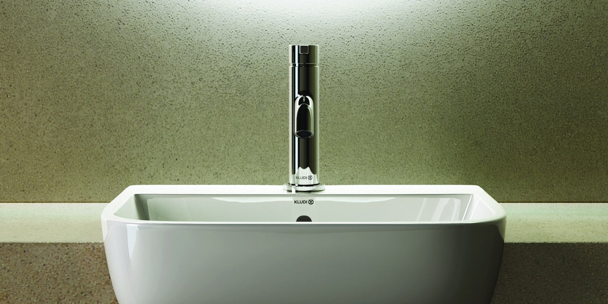 Wall-hung washbasin with a tall basin mixer under a backlit mirror