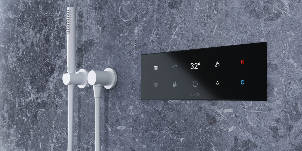 Electronic shower control panel on a marble wall beside a hand shower
