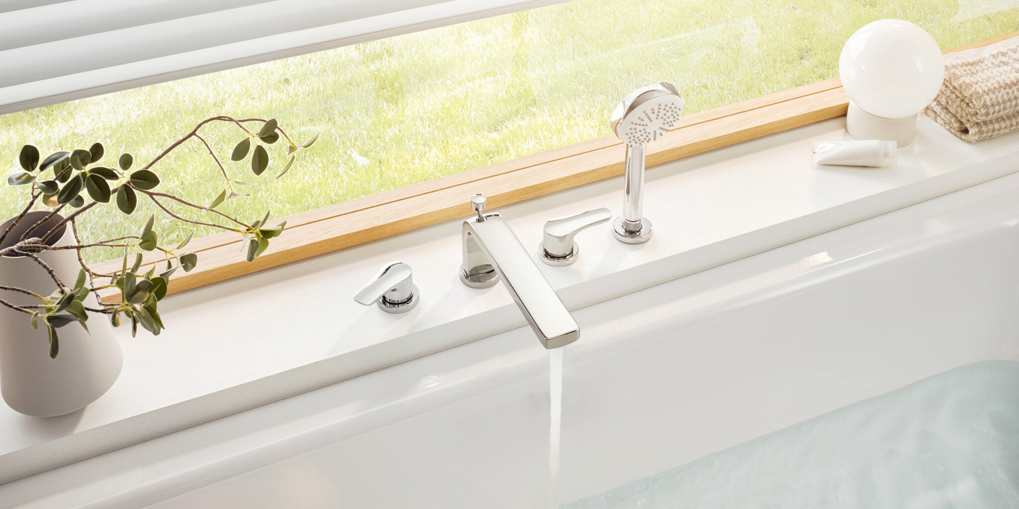 Bath under a garden window with a deck-mounted bath set and hand shower